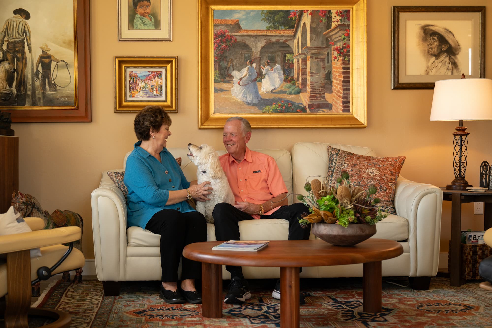 senior couple sit on their couch with their dog