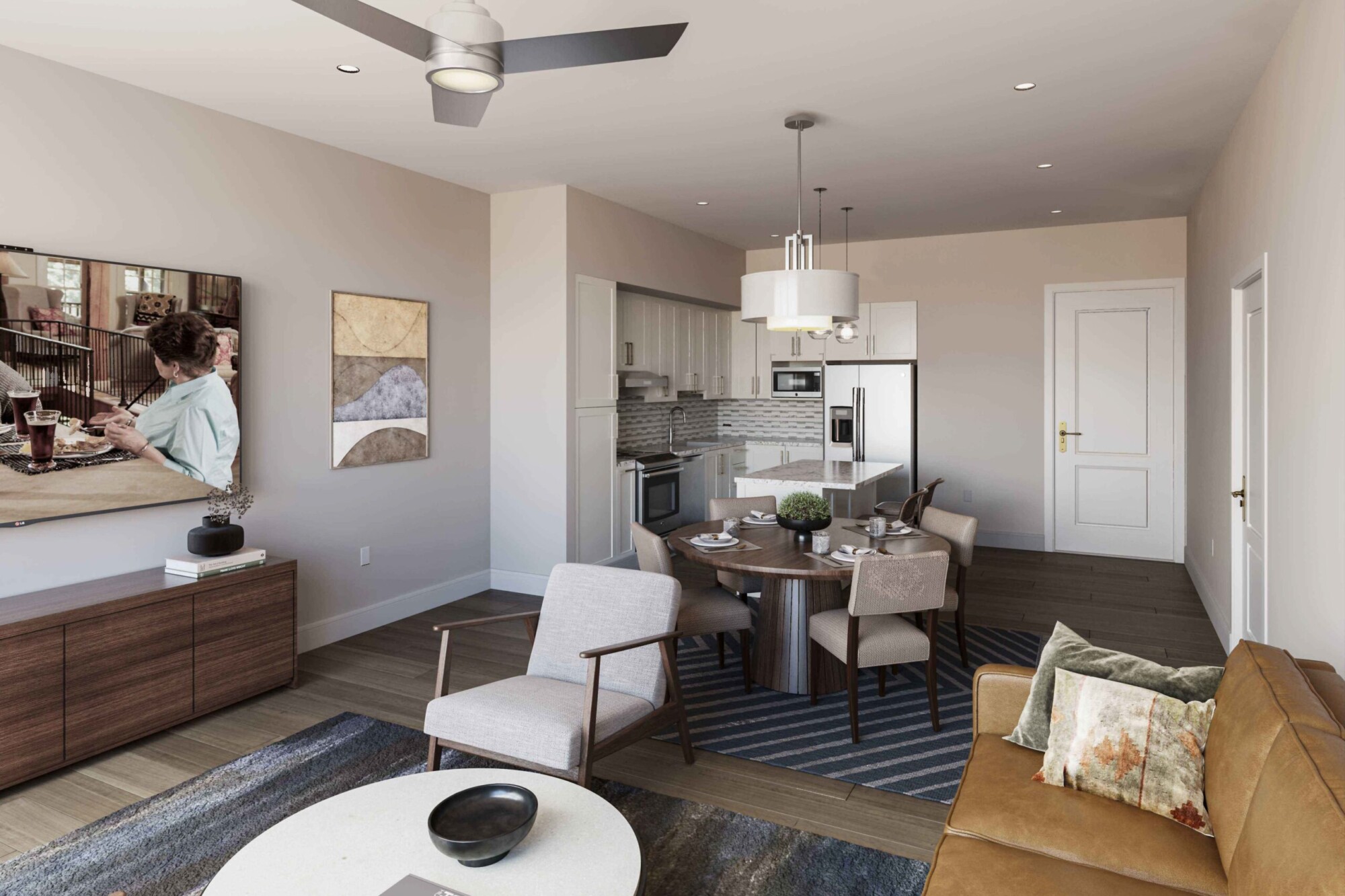 Lantana apartment interior showing a furnished open-concept living room, dining area and kitchen. The living space includes a tan leather sofa, accent chair, oval coffee table and television, while the kitchen features white cabinetry, stainless steel appliances, stone countertops and an island beside a round dining table.